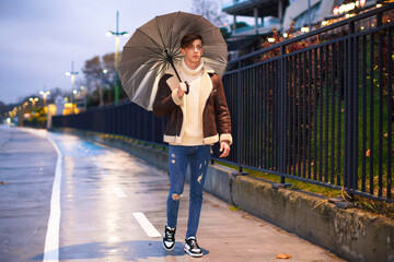 Man taking a walk in hand in the evening rainy weather. Young male taking an umbrella for a walk in the cold and rainy winter weather