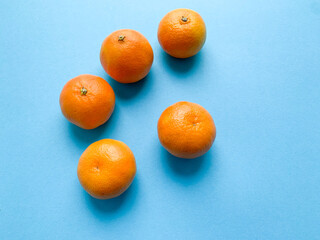 Ripe, fresh tangerines on a blue background. Photo from above. winter fruit season. fresh fruit, vegetarian. Association of Winter and Christmas holidays.