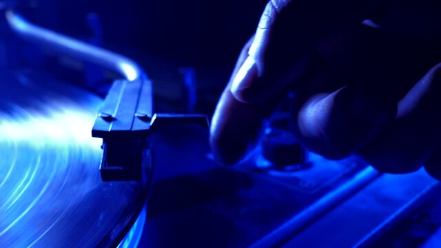 hands placing the vintage turntable on a spinning vinyl record. the vinyl record is spinning. the needle plays on a vintage vinyl record