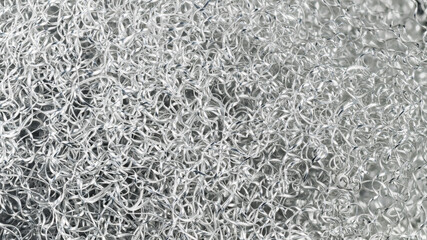 Black and white background of aluminum swarf tangled on heap. Close-up of shiny silvery spiral...