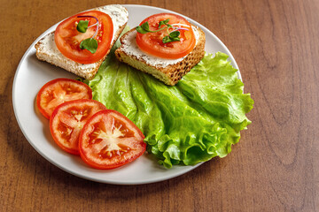 dried diet bread with curd cheese, tomatoes and lettuce on a ceramic plate