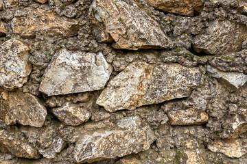 stone wall dark brown old and weathered from many stones blocks background