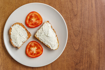 dried diet bread with curd cheese and sliced tomatoes on a ceramic plate