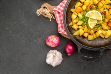 Fototapeta na wymiar top view fried potatoes inside pan with lemon on dark background dish cuisine meal food color dinner