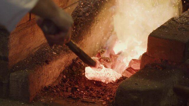 Red hot glowing ingot hammered on anvil then put back in coal forge, Blacksmith