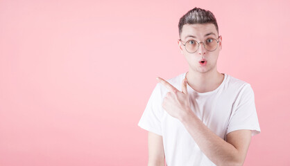 Portrait of young man with shocked facial expression point to aside copyspace with his forefinger