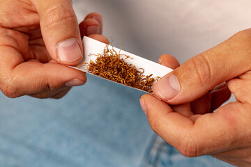 Male hands rolling tobacco in cigarette paper