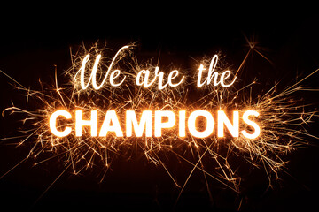 'We Are The Champions' in dazzling sparkler effect on dark background