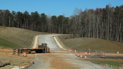 Fototapeta na wymiar Tractor towing flat bed trailer at a new highway construction site in Mississippi, USA 