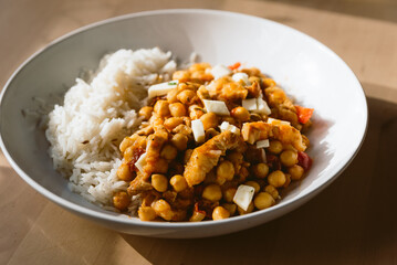 close up of vegetarian chickpea curry dish with basmati rice. Simple homemade traditional dish on wooden table with warm light