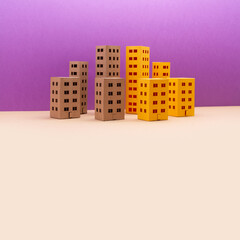 Naklejka premium Miniature city with yellow brown houses on purple beige background. Abstract urban architecture landscape, simplified town layout with high-rise buildings, skyscrapers with many windows. copy space