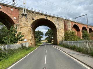 View along, Shay Lane, with a stone and brick built viaduct, set against a cloudy sky in, Walton, Wakefield, UK