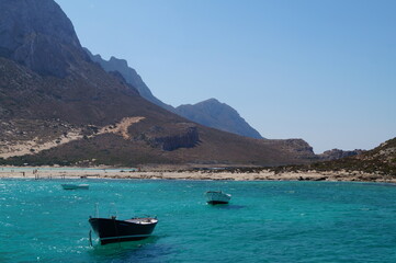 Fototapeta na wymiar Coast on a sunny day, turquoise clear water and boats.