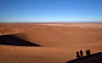 Fototapeta na wymiar Silhouette von Menschen auf einer Sanddüne mit Blick auf die Wüste