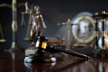 Law symbols composition. Judge’s gavel, Themis  statue, scale, hourglass and old clock on the shining wooden brown table and the gray background.
