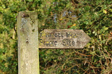 Old wooden sign pointing to Whipcott Wharf picnic site on the Grand Western canal in Somerset
