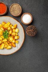 top view tasty fried potatoes inside plate with seasonings on dark desk color oil kitchen dinner food photo