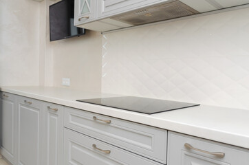 Beautiful classic kitchen in light grey and white tones with induction cooker