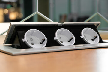 Three hidden sockets on a wooden kitchen countertop close-up, copy space