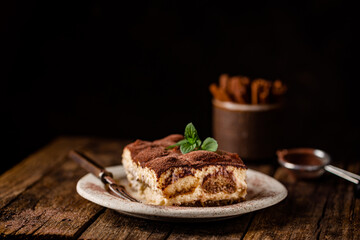 Piece of traditional Italian dessert tiramisu on dark background