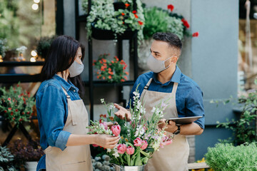Florists stand on counter focused on bouquet for client