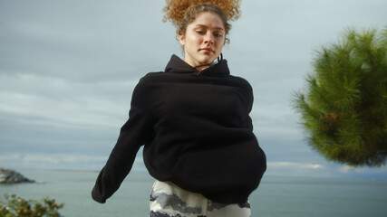 Fit young woman squatting and jumping in park close-up.