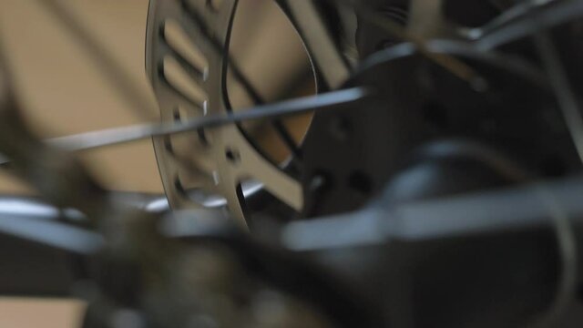 Slow rotating movement of bicycle hub, spokes, brake disc and chain. Close up of bike parts.