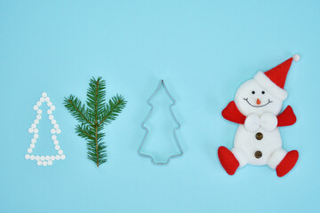 Snowman figurine and Creative Christmas tree made of pills on blue background. Spruce twigs. New Year, Christmas card.
