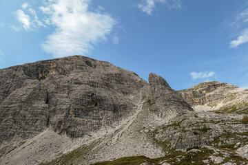 A close up view on a high and desolated mountain peak in Italian Dolomites. The lower parts of the mountains are overgrown with moss and grass. Raw and unspoiled landscape. A bit of overcast.