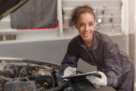 Portrait happy worker African American woman work for auto mechanic in garage checking car engine.
