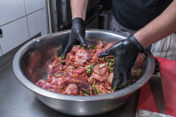 The chef marinates pork meat. Delicious food in the restaurant