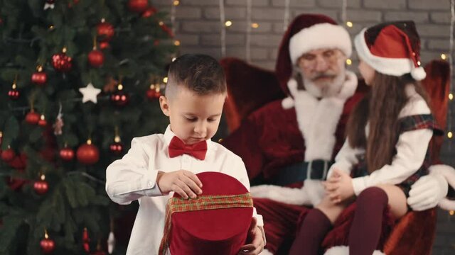 boy opening his present Christmas tree woman holiday xmas gift Santa happy decoration celebration beautiful young red winter child present people beauty smile happiness new year hat box white family