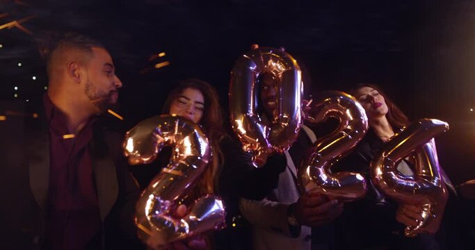 Group of friends holding 2024 balloons and sparklers celebrating new years