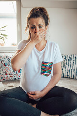 A pregnant woman suffering from sickness at home.