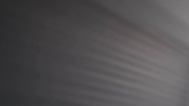 Blurry dark shadows moving on the wall. Spooky shadow art noise texture. closeup the motion of shadow batten of lath light on white wall texture background. Slow motion video. stock footage