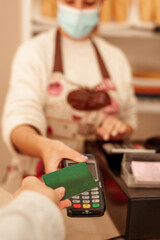 Using credit card to pay at bakery store wearing surgical mask. New normal concept.