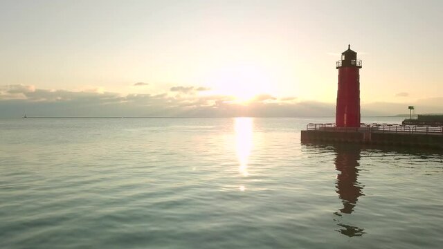Milwaukee Wisconsin red light house on the coast of Lake Michigan with a bright dreamy sunrise in the distance. Great footage for establishing or text to the left.