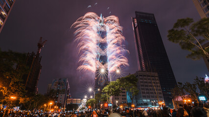 Taipei City Night landscape and Taipei 101 skyscraper is lit up by fireworks. People watching and...