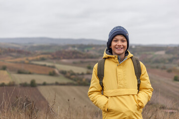 Happy little boy enjoying on a hill in autumn day.