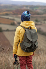 Back view of small boy with binoculars during autumn day in a meadow.