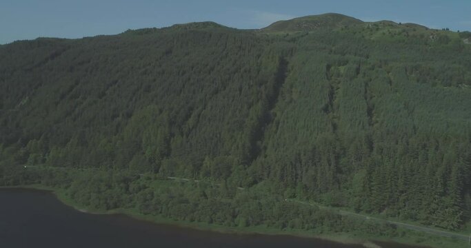 Aerial of cars travelling along a mountain road beside a loch in the Scottish Highlands