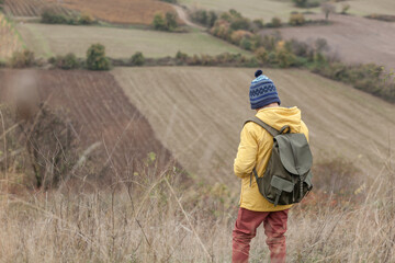Rear view of little hiker in tall grass on a hill.