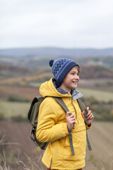 Happy little boy enjoying during autumn day on a hill.