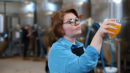 Portrait of woman brewer holding glass with craft beer and drinking