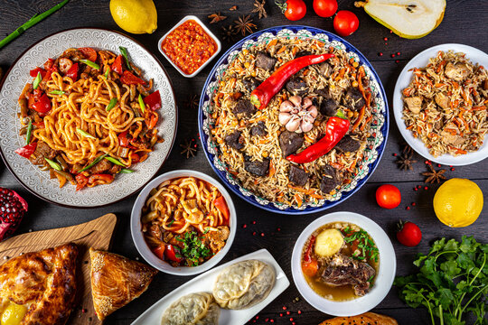 The concept of oriental cuisine. Assorted Uzbek food set, pilaf, samsa, lagman, manta, shurpa central asia food. Homemade Uzbek pilaf or plov from lamb served in cast iron cookware