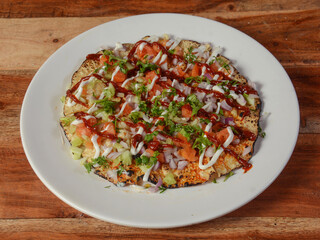 Masala Papad is a delicious Indian snack made using roasted or fried papad topped with a tangy and spicy onion tomato mix, served over a rustic wooden background, selective focus