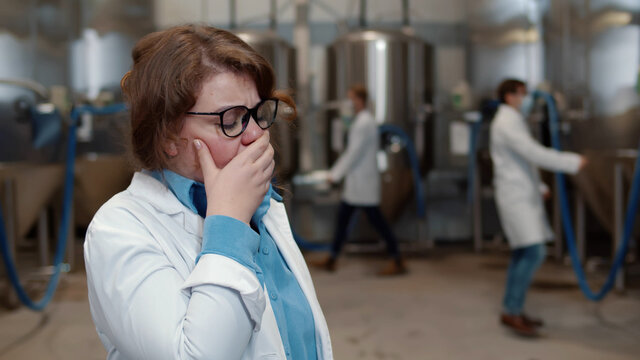 Portrait of woman scientist coughing in factory plant