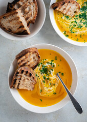 Pumpkin soup served in a bowl with croutons, parsley and olive oil.