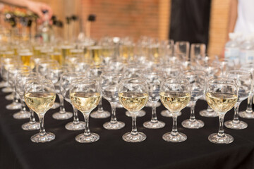 Close up of glasses of champagne on the table with shallow depth of field. Banquet black table with white wine