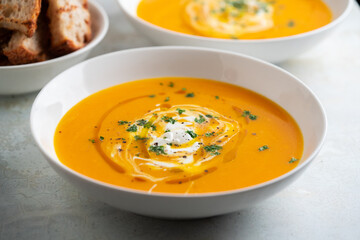 Pumpkin soup served in a bowl with croutons, parsley and olive oil.